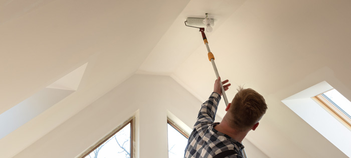 Handyman painting a ceiling with a roller